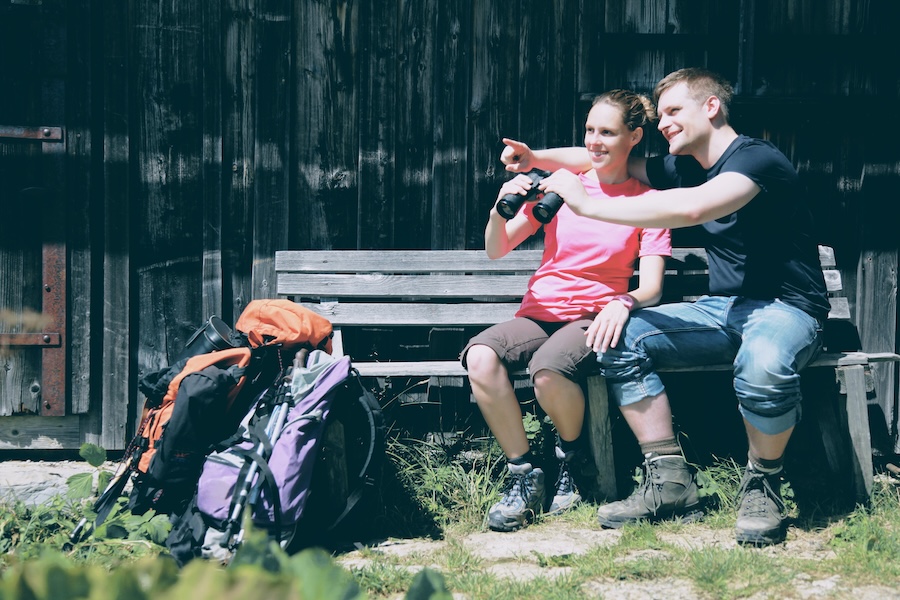 Ein Paar beim Wandern vor einer Berghütte – symbolisiert den Wert der Gemeinsamkeit und des gemeinsamen Erlebens in der Natur