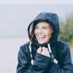 Junge Frau lacht herzlich und strahlt vor weiblicher Energie.