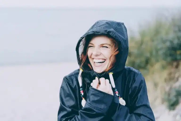 Junge Frau lacht herzlich und strahlt vor weiblicher Energie.