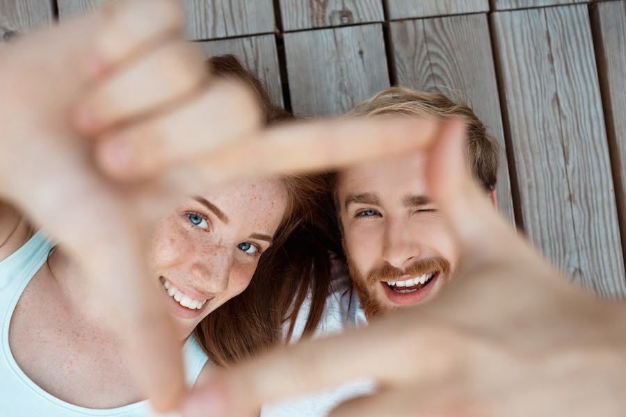 Young beautiful couple smiling, lying on wooden boards.