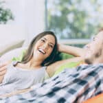 Ein glückliches Paar entspannt auf einem Sofa, lacht und unterhält sich in einer gemütlichen und freundlichen Umgebung.