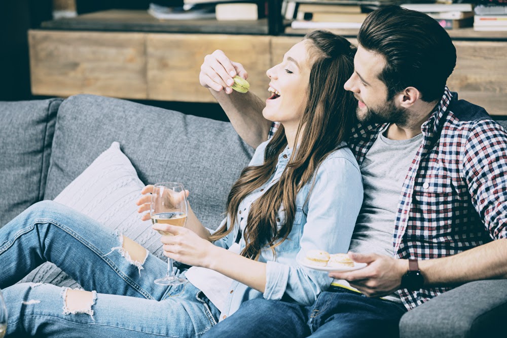 Glückliches Paar Mitte 30 sitzt entspannt auf der Couch – symbolisiert erfolgreiche Partnersuche und harmonische Beziehung Glückliches Paar Mitte 30 sitzt entspannt auf der Couch – symbolisiert erfolgreiche Partnersuche und harmonische Beziehung