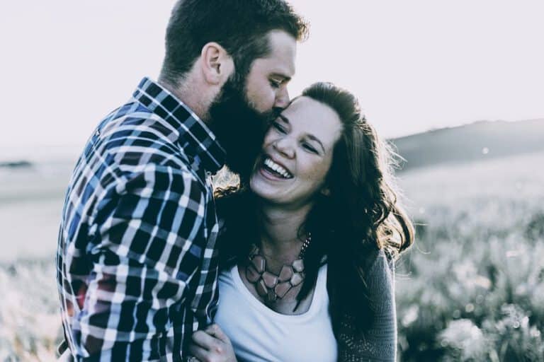 Ein junges Paar umarmt sich liebevoll in der Natur – Symbol für romantische Zweisamkeit im Kontrast zur Frage: "Warum bist ich noch Single?"
